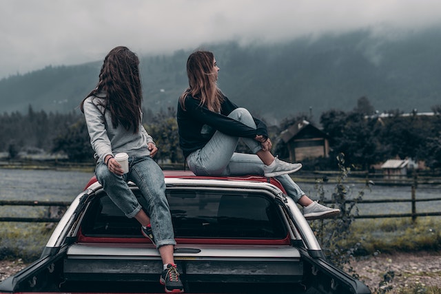 Two women sitting on car