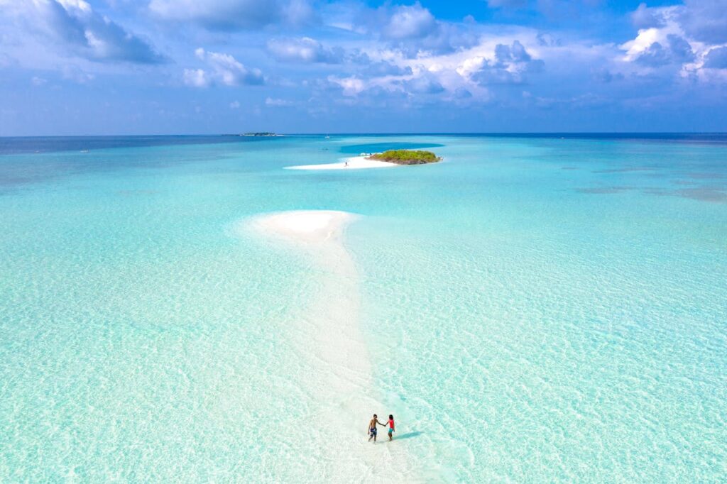 Couple walking along a sandbar in the Maldives